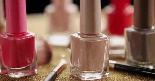 Colorful Nail Polish Bottles with Makeup Brushes on Gold