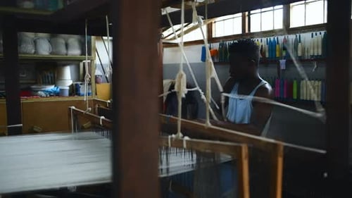 Man, floor treadle loom and textile production at clothing factory, manufacturing and craftsmanship