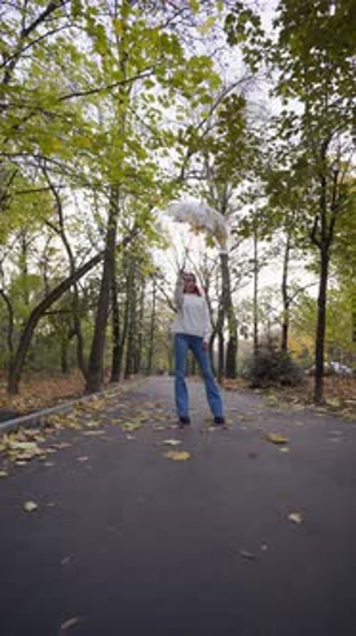 Mulher feliz levanta um guarda-chuva do qual voam folhas amarelas de outono