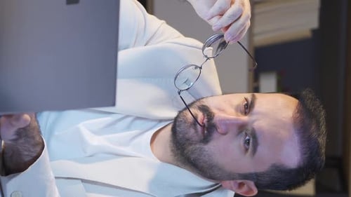 Vertical video of Businessman working at night using laptop.