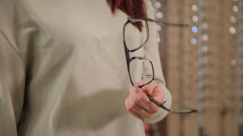 An Individual is Elegantly Holding a Pair of Eyeglasses Emphasizing Stylish Eyewear Within a