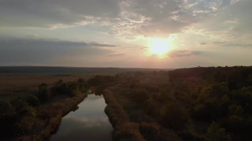Aerial shot of river in green valley at sunset