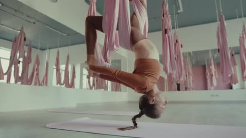 Woman Inverted in Aerial Yoga Swing in Studio
