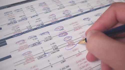 Hand Analyzing Financial Document with Pen Close Up