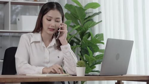 Woman Talking on Phone and Taking Notes