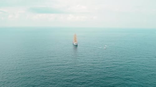 Ein einsamer Großsegler segelt auf offener See, an Sommertagen unter bewölktem Himmel.