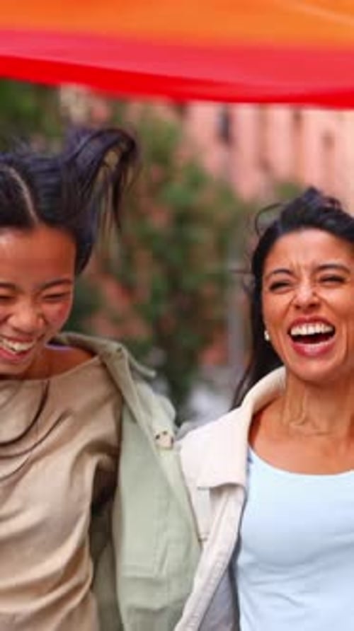 Joyful Lesbian Couple Waving Rainbow Flag Marching at Pride Parade