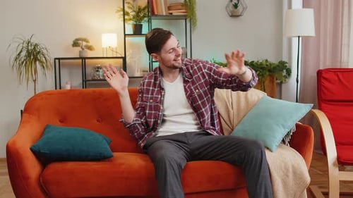 Man Singing Dancing Celebrate Victory Win Enjoying Music Sitting on Couch in Living Home Room