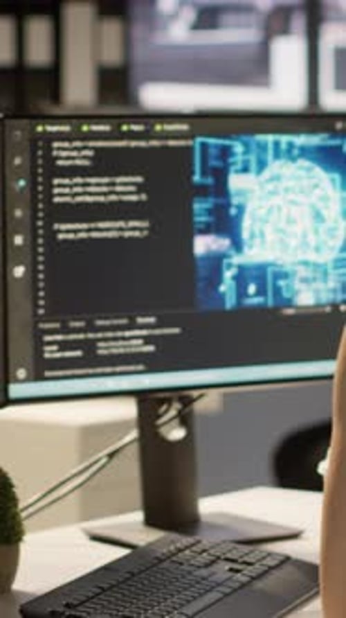 Woman Coding with Colleague at Computer in Office