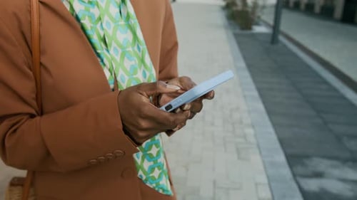 Anonymous Businesswoman in Brown Coat with Green Scarf Chatting on Phone