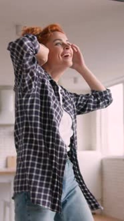 Happy woman dancing to music in apartment
