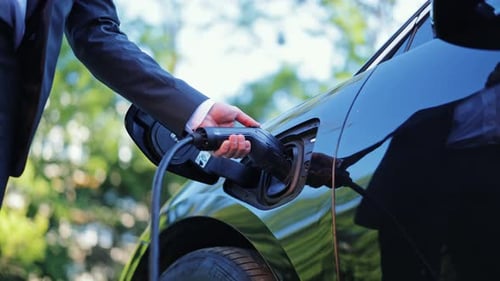 Businessman Plugs Electric Car for Sustainable Energy and Future Transportation