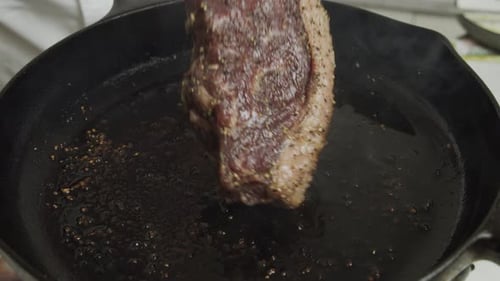 Frying meat steak inside frying pan. Close up slow motion shot.