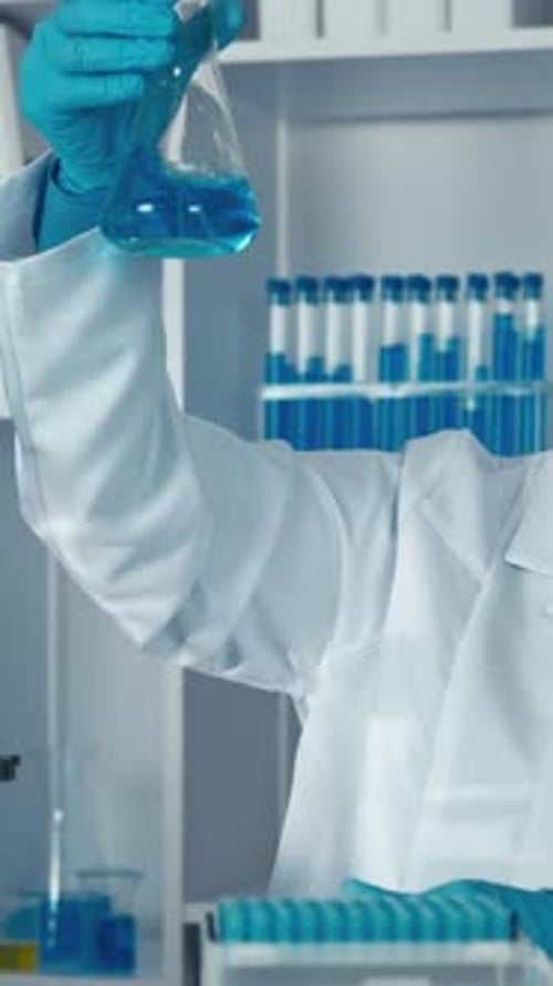 Female Scientist Holds Flask with Blue Liquid in Lab