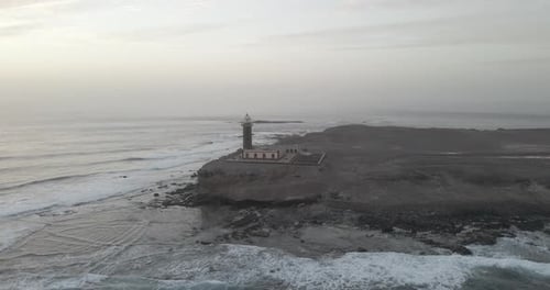 Captured in breathtaking aerial footage, a resilient cliffside lighthouse overlooks the vast ocean,