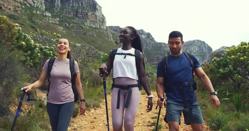 Hikers walking down a trail on a mountain with hiking sticks
