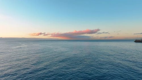 Sunset view over calm ocean waters at coastal pier location