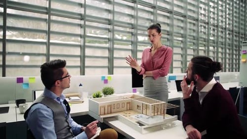 Young architects discuss house model design in modern office workplace