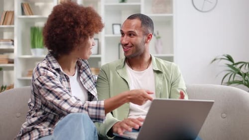 Young Couple Using Laptop Computer on Couch at Home
