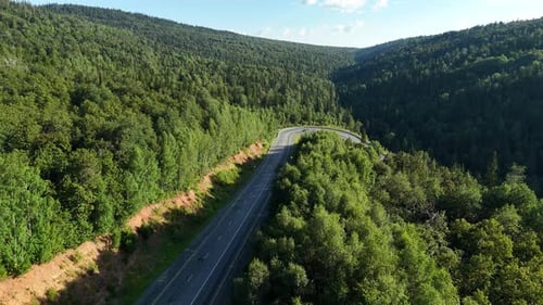 Aerial View of Mountain Highway Sharp Curve Through Green Forest Valley