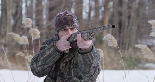 Man Aims Firearm During Snowy Winter Hunt