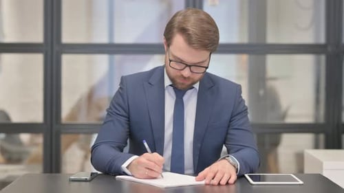 Young Businessman Writing a Letter in Office