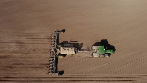 Grüner Traktor pflanzt Sonnenblume auf dem Sandfeld in der Ukraine 4K