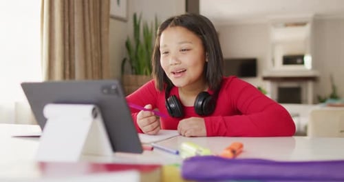 Girl Interacts with Tablet Computer during Online Lesson
