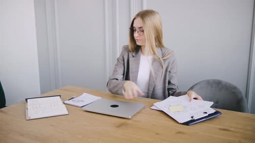 Young Woman Organizes Documents at Desk