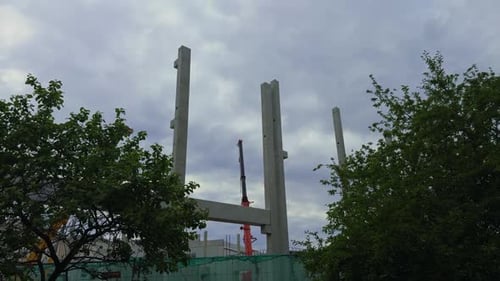 Un sitio de construcción detallado con columnas de concreto contra un cielo nublado que muestra el tiempo real