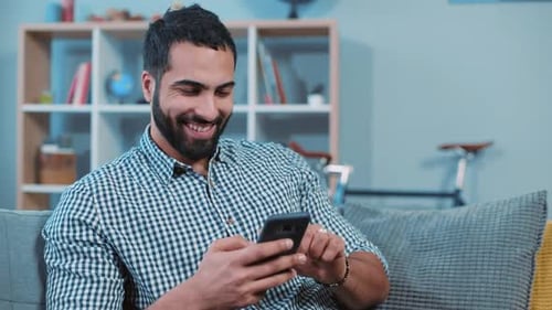 Happy Young Man Typing Message on the Phone Smiling Feel Happy Sit on Sofa Home Portrait Close Up