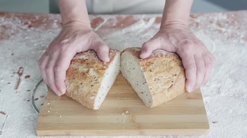 Ein professioneller Bäcker präsentiert frisch geschnittenes und knuspriges Brot direkt aus dem Ofen. Zeitlupe.