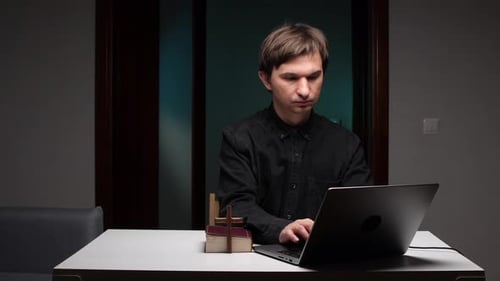 Priest Holding Cross and Leading Online Church Service with Laptop and Bible