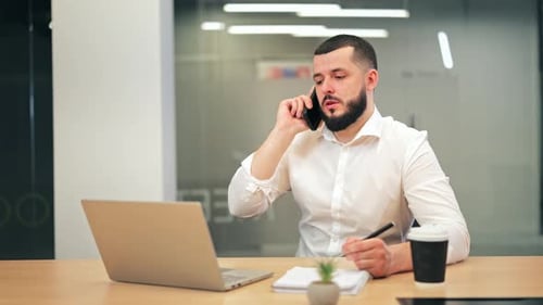 Focused Businessman Engaged in Phone Call at Office Desk