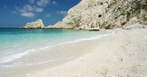 Clear sea waves splashing on peaceful white beach with pebbles, seascape with rocks in background