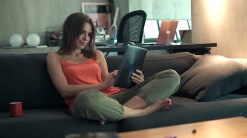 Woman Using Tablet Device on Sofa at Home