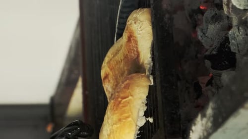 Grilling bread for hamburgers. Turning bread left on a smoky grill. Vertical video