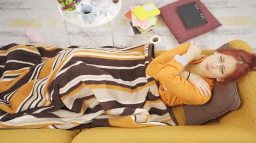 Woman Lying on Couch Clutching Arm in Pain