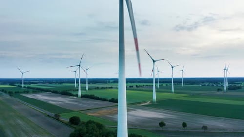 Aerial drone shot of windmills in industrial renewable energy technology park with tall wind turbine