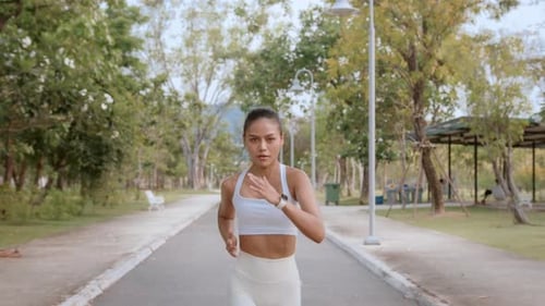 Young fitness woman in sportswear jogging in city park