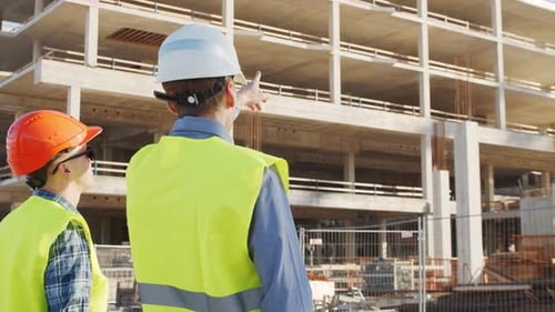 Professional Builders Standing in Front of Construction Site Office Building and Crane Background