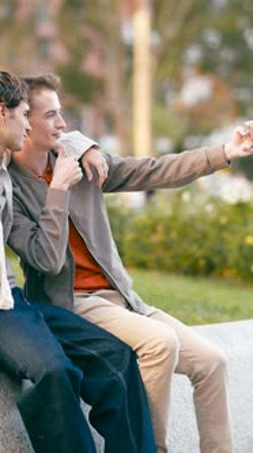 Two Young Men Sitting and Taking a Selfie
