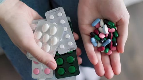 Close Up Tablets of Different Colors in Hands of Unrecognizable Many Pills and Medications