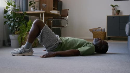 African American Man Performing Glute Bridge Exercise in Living Room