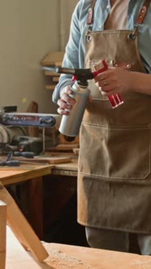 Vertical of Anonymous Craftsman Burning Wooden Piece with Blowtorch in Workshop