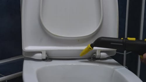 Hand Using Steam Cleaner to Clean Toilet