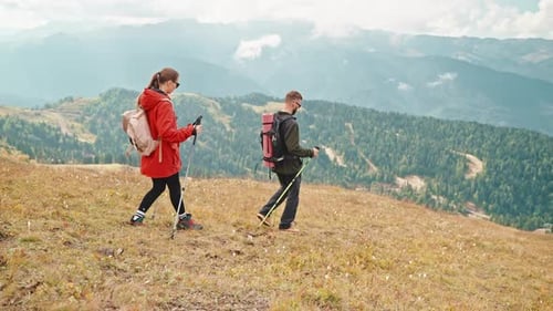 Couple Hiking Down Mountain Trail with Trekking Poles