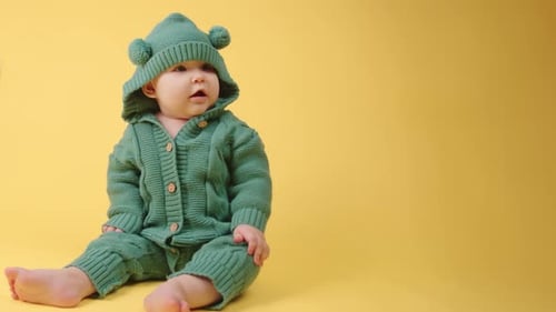 Portrait of a cute baby in a warm knitted jumpsuit with a hood