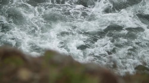 Turbulent sea waters with rock in the foreground.