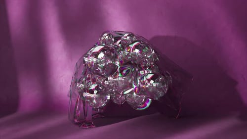 Bolas de arco-íris transparentes e lisas se movem em um fundo roxo, onda, closeup, capa transparente em cima de